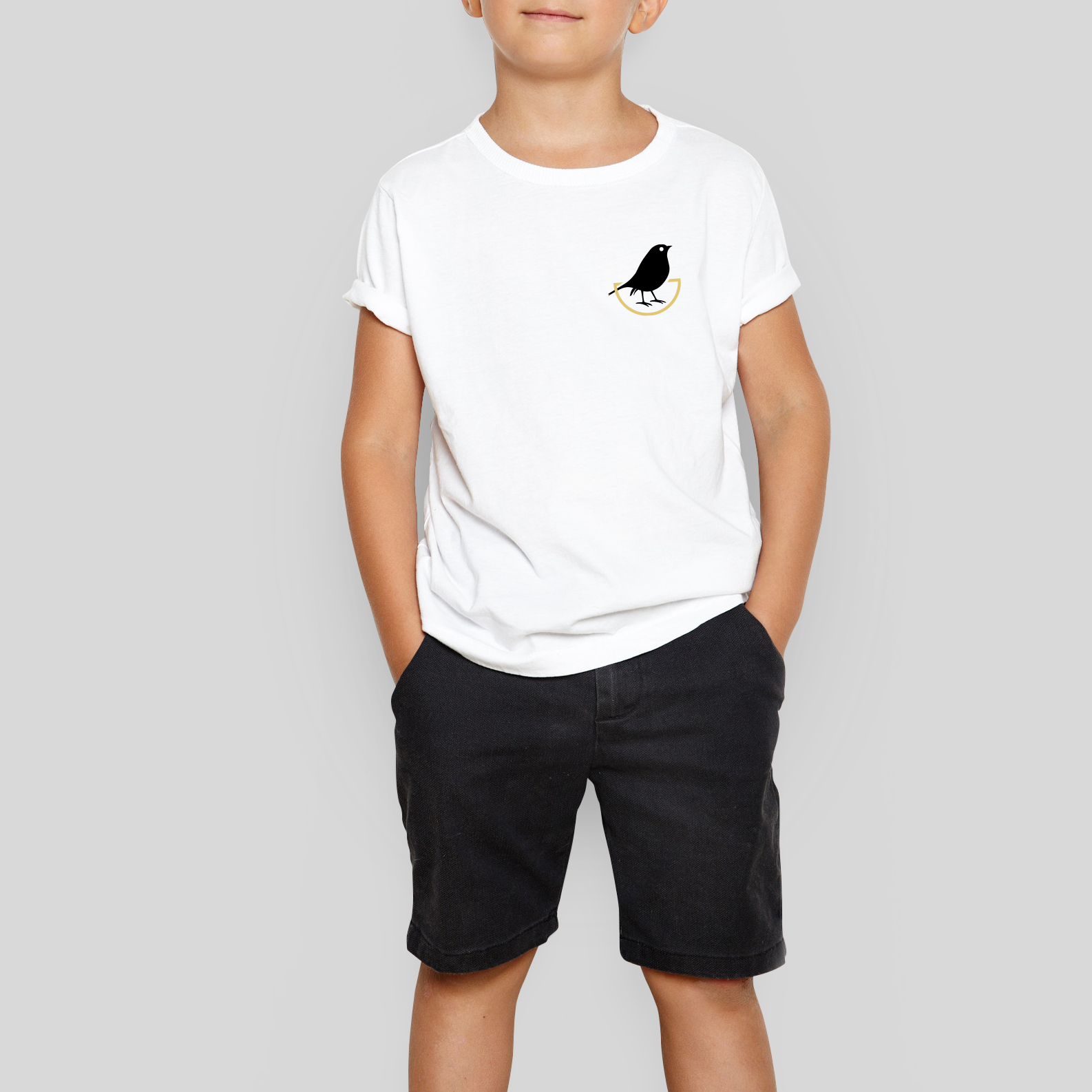 A young child wearing a white tshirt with the Nest School emblem on it.